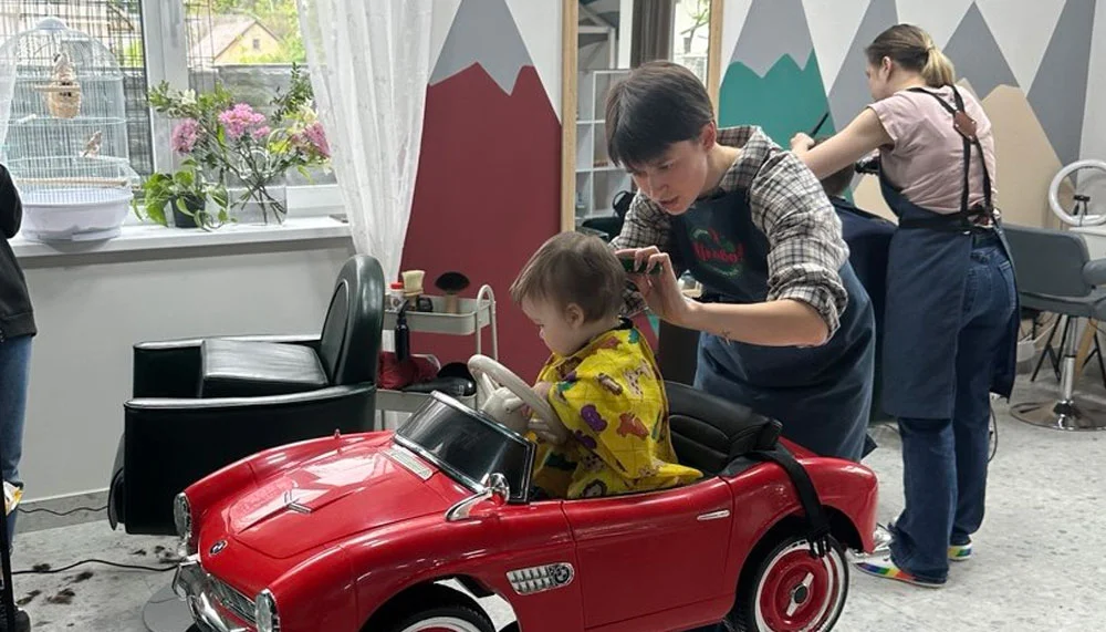 Дитині стрижуть волосся у кріслі, виконаному у формі автомобіля у перукарні theЦікаво